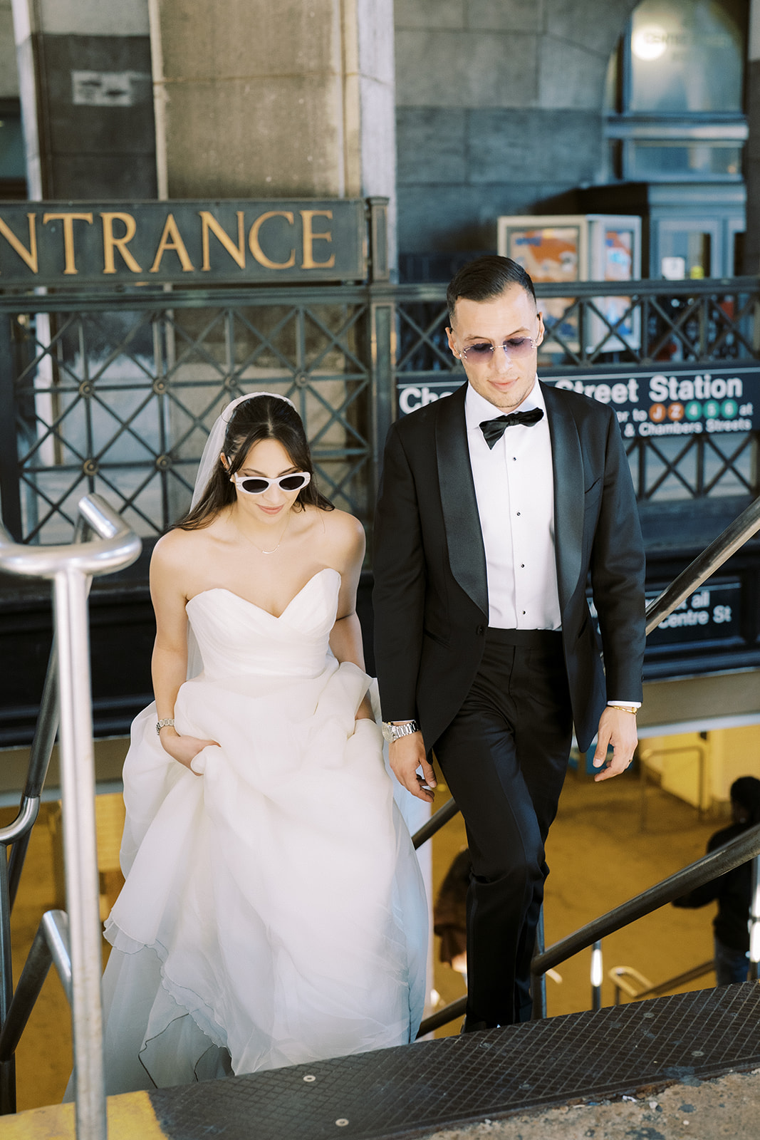 newlyweds in nyc wearing sunglasses and taking the subway