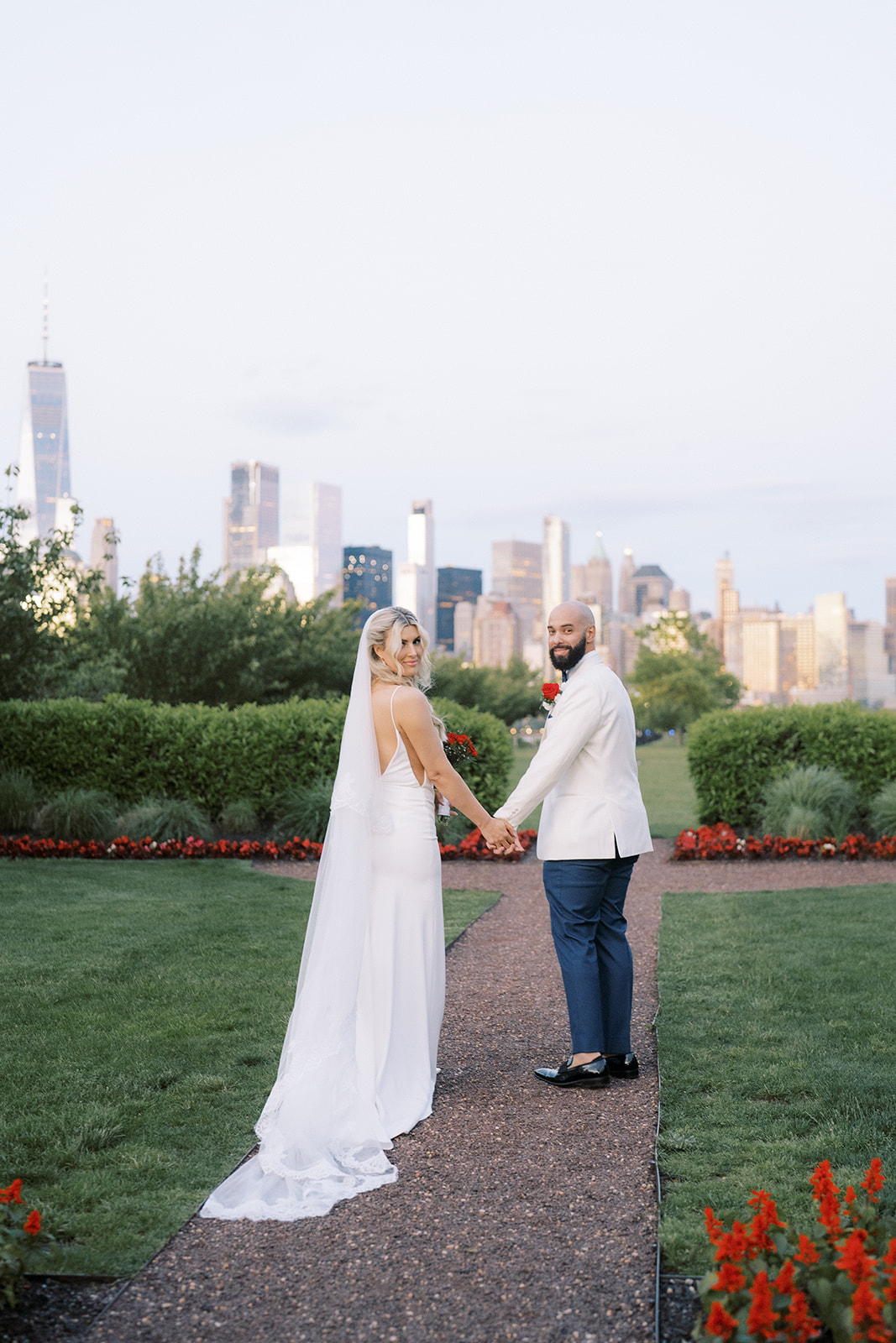 bride and groom walking at Maritime Parc venue with Manhattan backdrop at sunset
